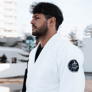 White Pantera Negra BJJ Gi with black circular patch and brown belt, symbolizing intermediate martial arts proficiency