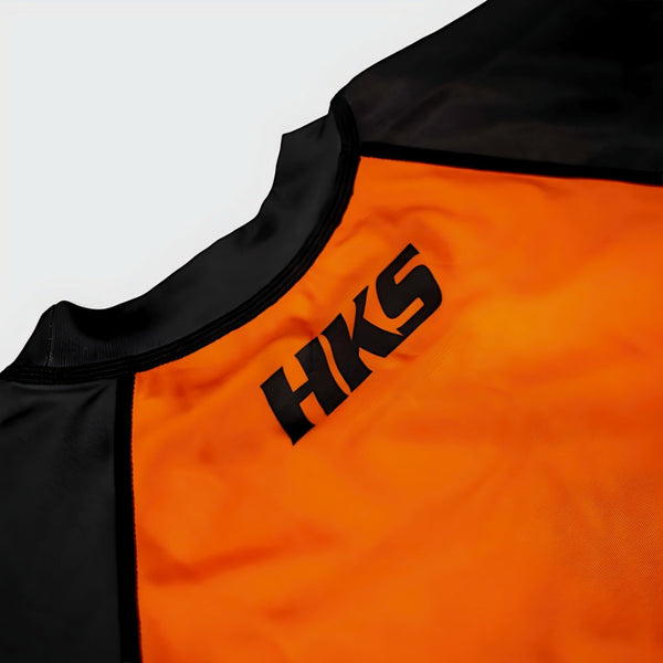 Hooks Kids 2026 Ranked BJJ Rash Guard Orange, close-up of chest and neckline showing HKS logo on orange and black fabric