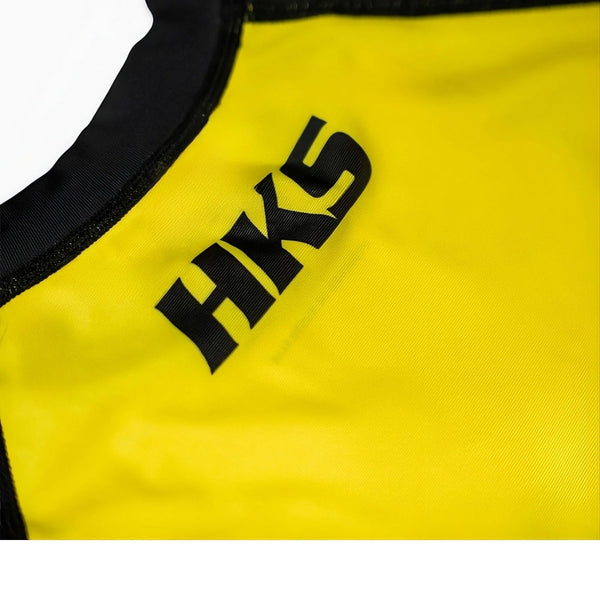 Hooks Kids 2026 Ranked BJJ Rash Guard Yellow, close-up of chest showing HKS logo print and black neckline trim