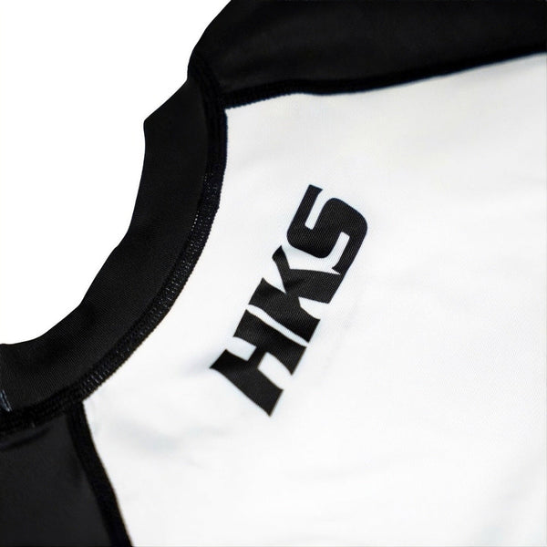 Hooks Kids 2026 Ranked BJJ Rash Guard White, close-up of chest and neckline showing HKS logo and black collar stitching