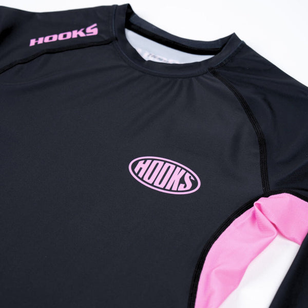 Hooks Long Sleeve Rash Guard Rose Noir, close-up of chest showing pink oval logo and pink side panel detail
