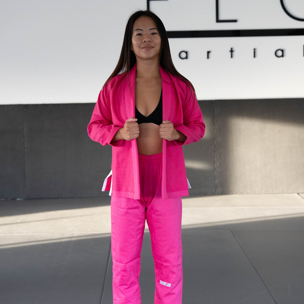 Hooks Pastel BJJ Gi in pink, front view worn open over a sports bra, white belt visible at the sides
