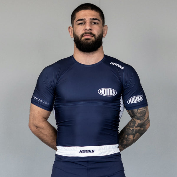 Hooks navy short sleeve BJJ rashguard, front view worn, white panel accents on cuffs and hem with oval chest logo