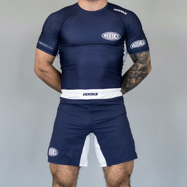 Hooks navy BJJ grappling shorts with white waistband and gusset panel, worn front view paired with matching rashguard