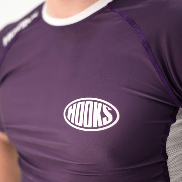 Hooks Fusion Short Sleeve Rash Guard Plum, close-up of chest logo and raglan seam, worn