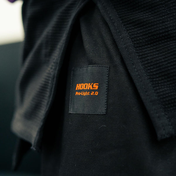 Hooks BJJ Gi Limited Edition Prolight Inferno, close-up of woven label with orange "Hooks Pro-Light 2.0" branding on black