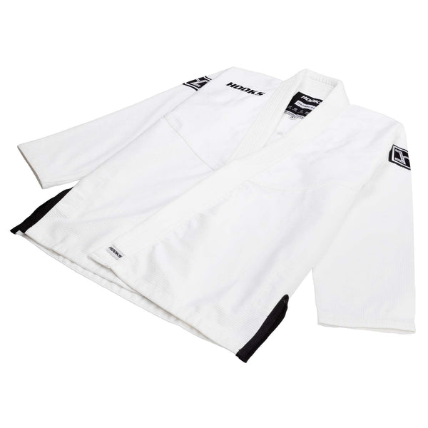 Hooks kids BJJ gi jacket, white with black trim, angled flat lay showing lapel, sleeve patch, and collar label