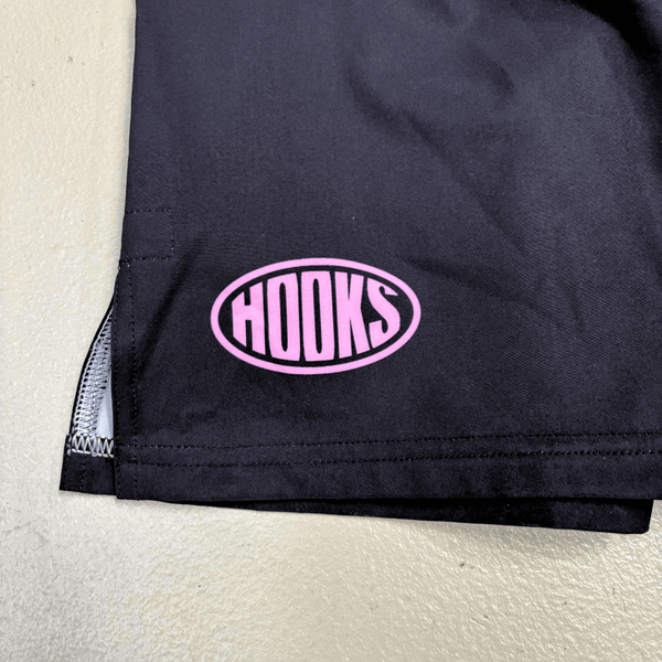 Hooks Sports Shorts Rose Noir, close-up of thigh logo — pink oval Hooks badge with triple-stitched hem and side split detail