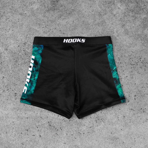Hooks Women's Flex Shorts Jungle Reign, front flat lay showing black shorts with teal botanical side panels and branded