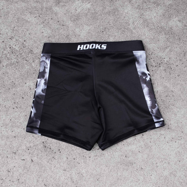 Hooks Women's Flex Shorts Black Mist, front flat lay showing black body with monochrome ink-wash side panels and branded