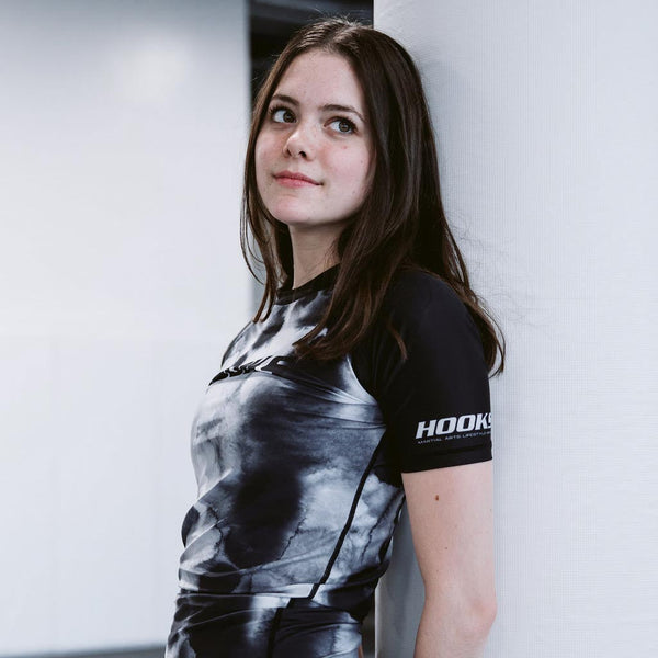 Hooks BJJ Short Sleeve Rash Guard Black Mist, worn, three-quarter front view showing tie-dye body and branded sleeve panel