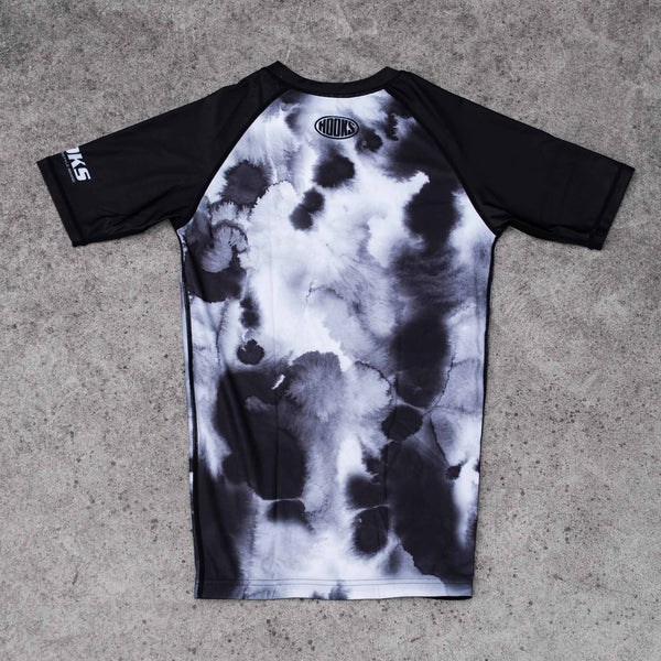 Hooks Black Mist short sleeve rash guard, back view flat lay showing ink-wash print body with black raglan sleeves