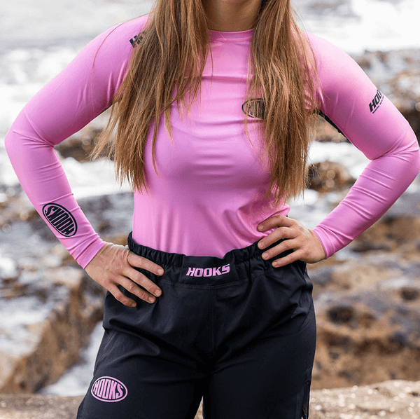 Hooks Long Sleeve Rash Guard Rose Fusion, front view worn, pink with logo at chest and cuff, paired with black Hooks shorts.