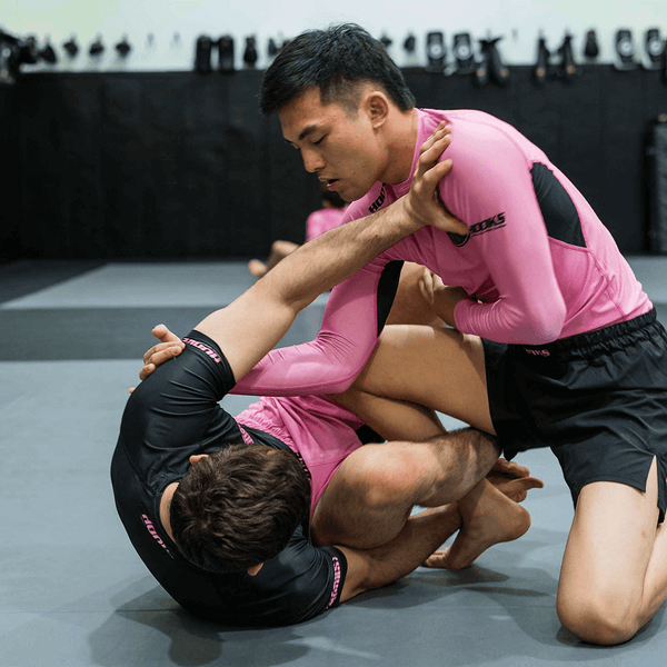 Hooks Long Sleeve Rash Guard Rose Fusion, worn during live grappling, paired with black shorts and black rash guard