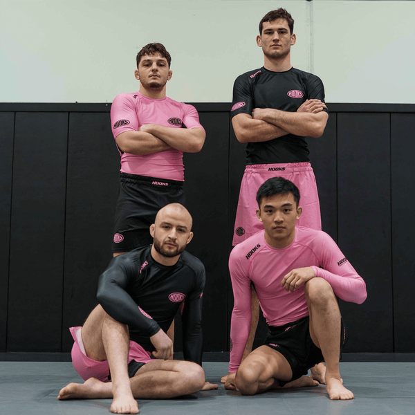Hooks Short Sleeve Rash Guard Rose Fusion, worn by four people on a mat showing pink and black colorway options