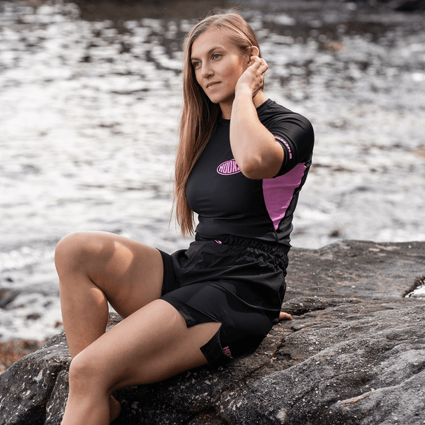 Hooks Rose Noir rash guard and shorts set, worn, showing black with pink side panel and oval chest logo