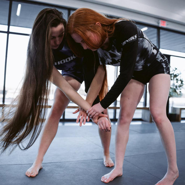 Hooks BJJ Long Sleeve Rash Guard in Black Mist, worn during live grappling, showing front and sleeve detail in action.