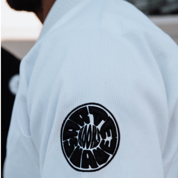 White Pantera Negra BJJ Gi sleeve with black circular ‘HOOKS’ patch, symbolizing premium martial arts apparel