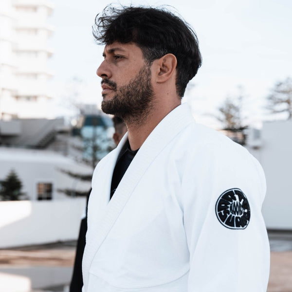 White Pantera Negra BJJ Gi with black circular patch and brown belt, symbolizing intermediate martial arts proficiency