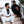 Two individuals in gis (one white, one black) sitting on steps, patches on sleeves, relaxed posture.