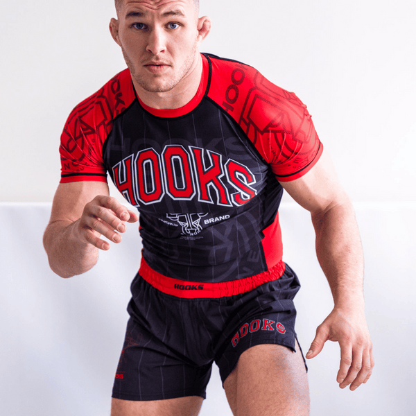 Man wearing a red and black 'Hooks' branded athletic outfit on a white background