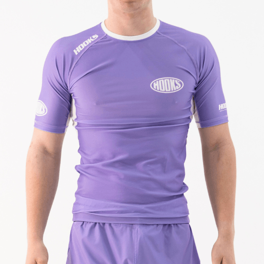 Hooks lavender short sleeve rash guard with white contrast panels and oval chest logo, front view worn by a person