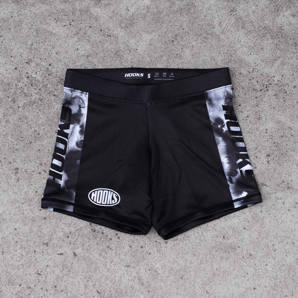 Hooks Women's Flex Shorts Black Mist, front flat lay showing black body with monochrome ink-wash side panels and oval logo